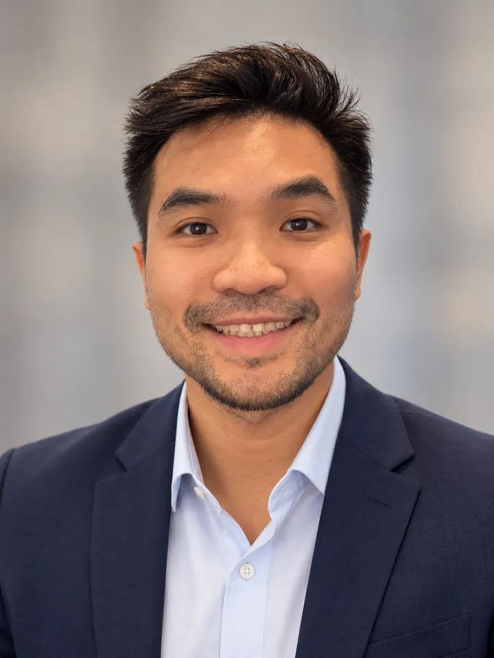 Tee Lakkhananukun smiling, wearing a navy blazer and white shirt.
